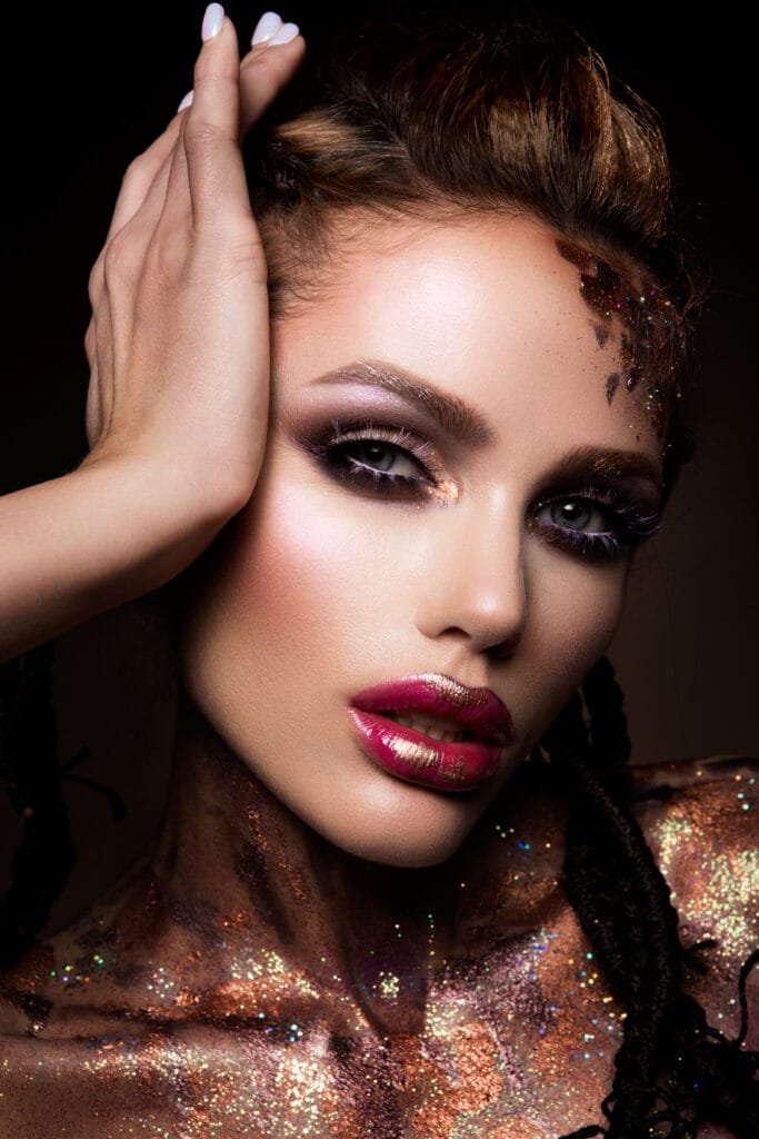 Fashion model with bright makeup and colorful glitter and sparkles on her face and body
