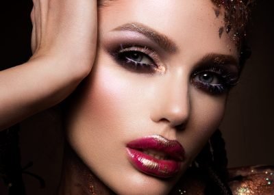 Fashion model with bright makeup and colorful glitter and sparkles on her face and body